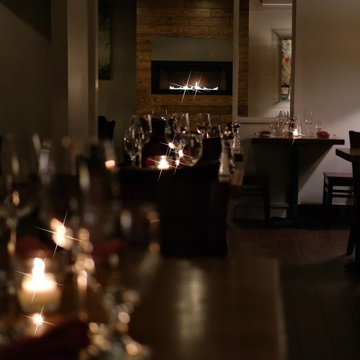 a dimly lit dining room with wine glasses on the table.