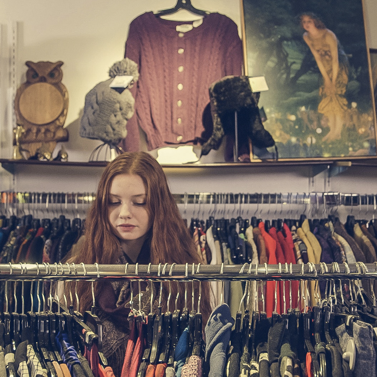 a woman looking at a rack of clothes.