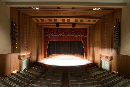 an empty auditorium with a stage and chairs.