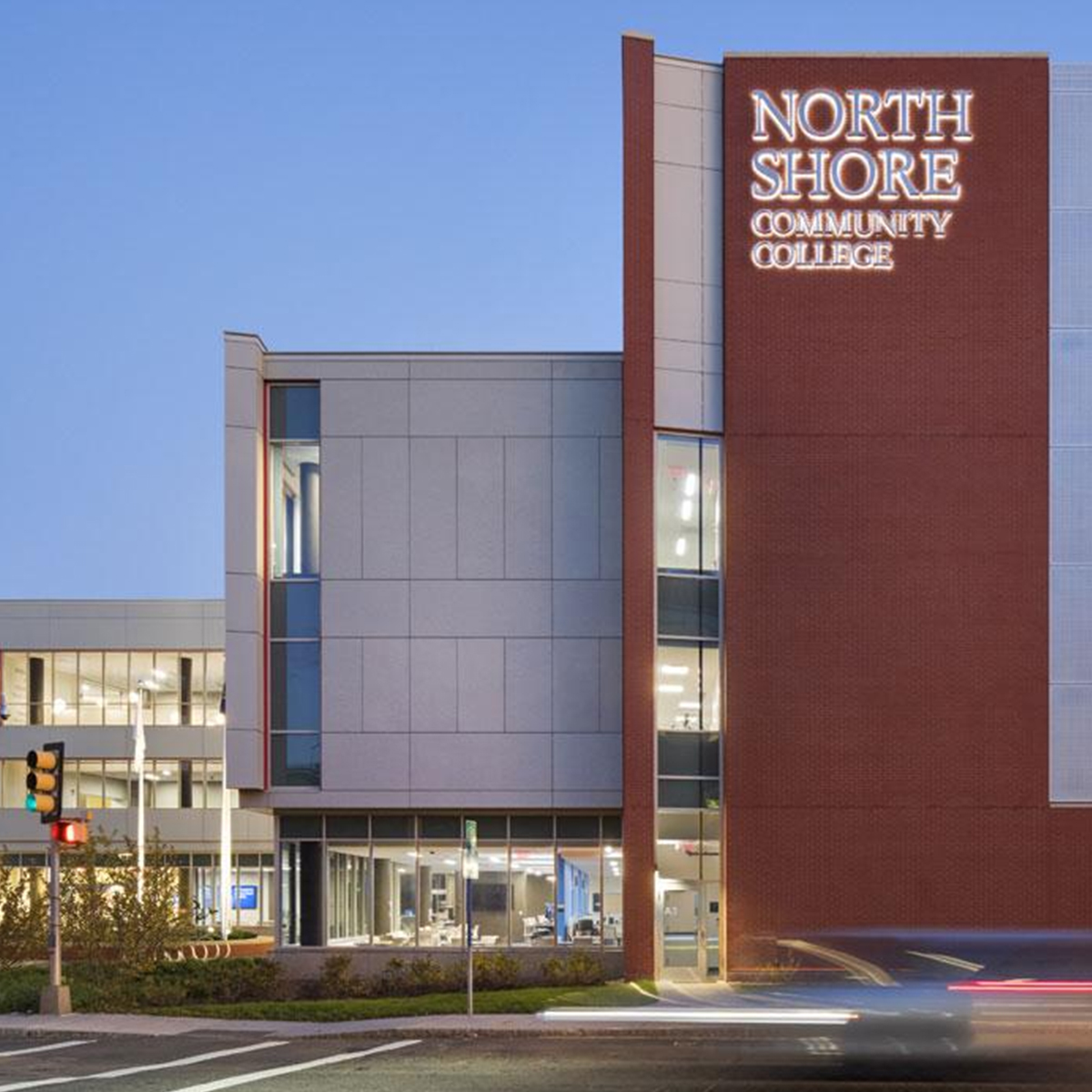 a car drives past a building with a sign that says north shore community college.