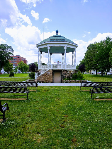 a gazebo sits in the middle of a grassy area.
