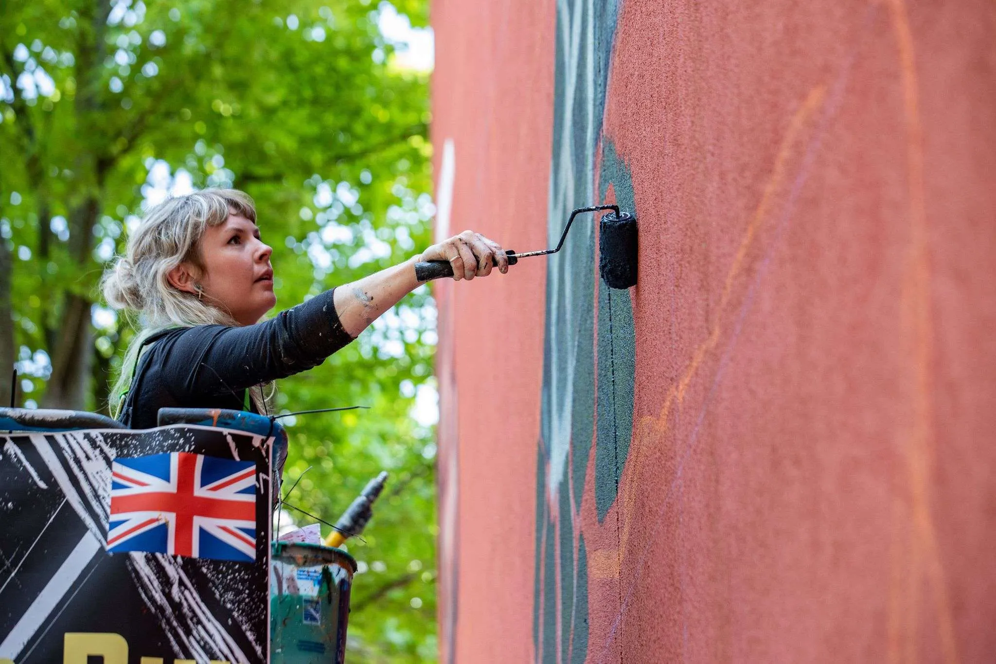 a woman painting a wall with a paint roller.