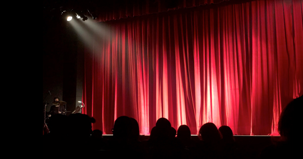 a stage with a red curtain and a spotlight.