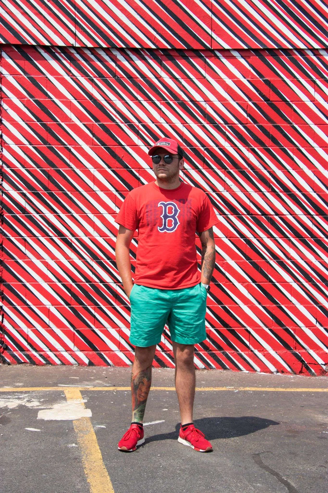 a man in a red shirt and green shorts standing in a parking lot.