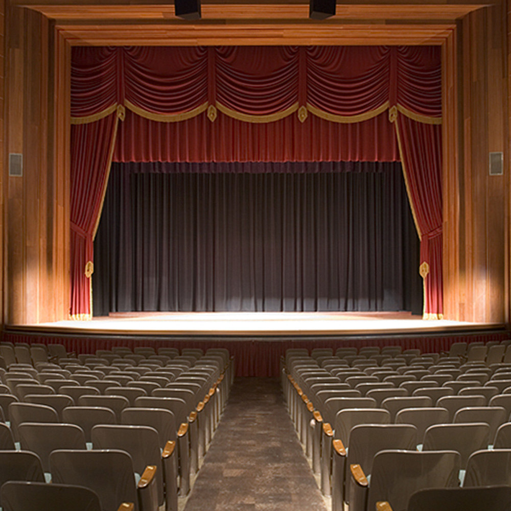 an empty auditorium with rows of seats and a stage.