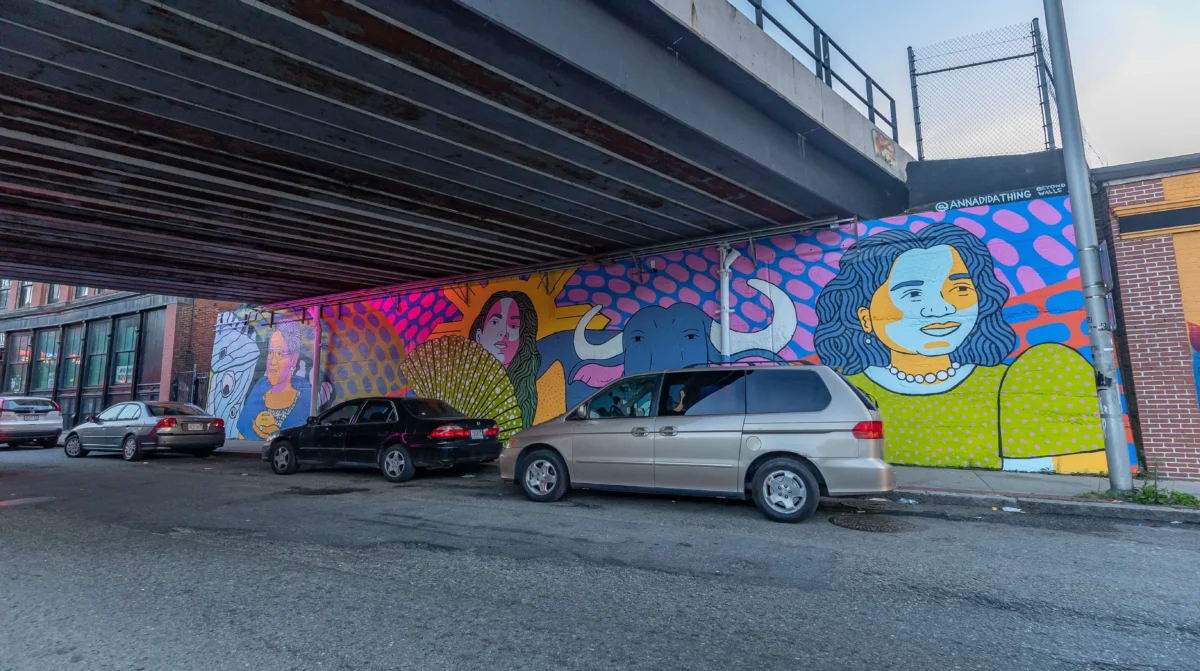 a car parked under a bridge with a mural on it.