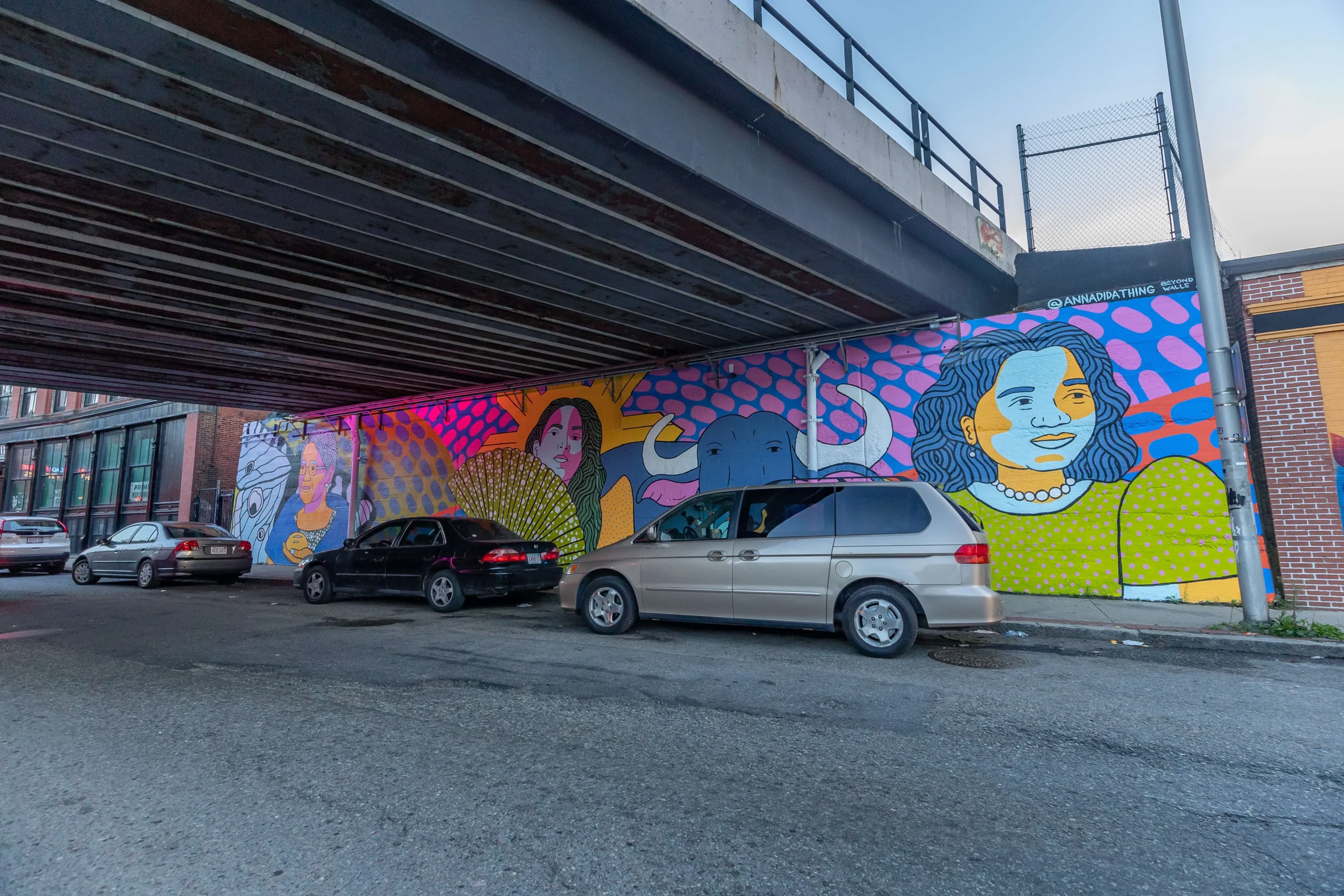 a car parked under a bridge with a mural on it.