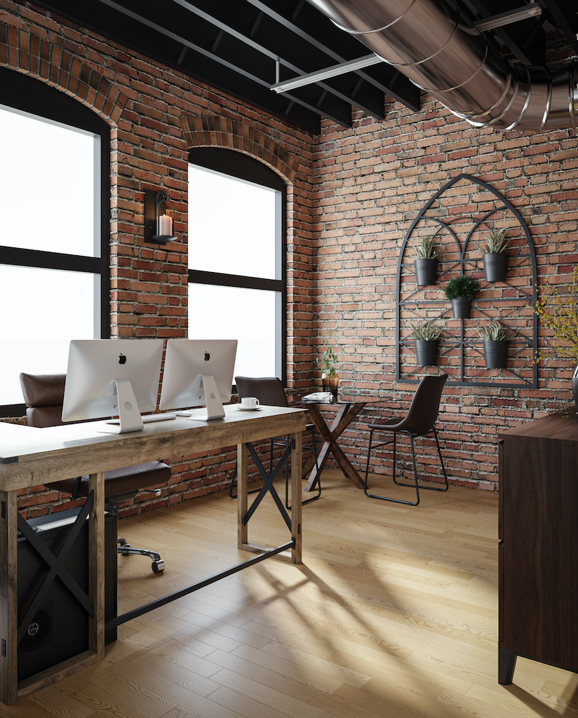 a brick wall in an office with two computers on a desk.