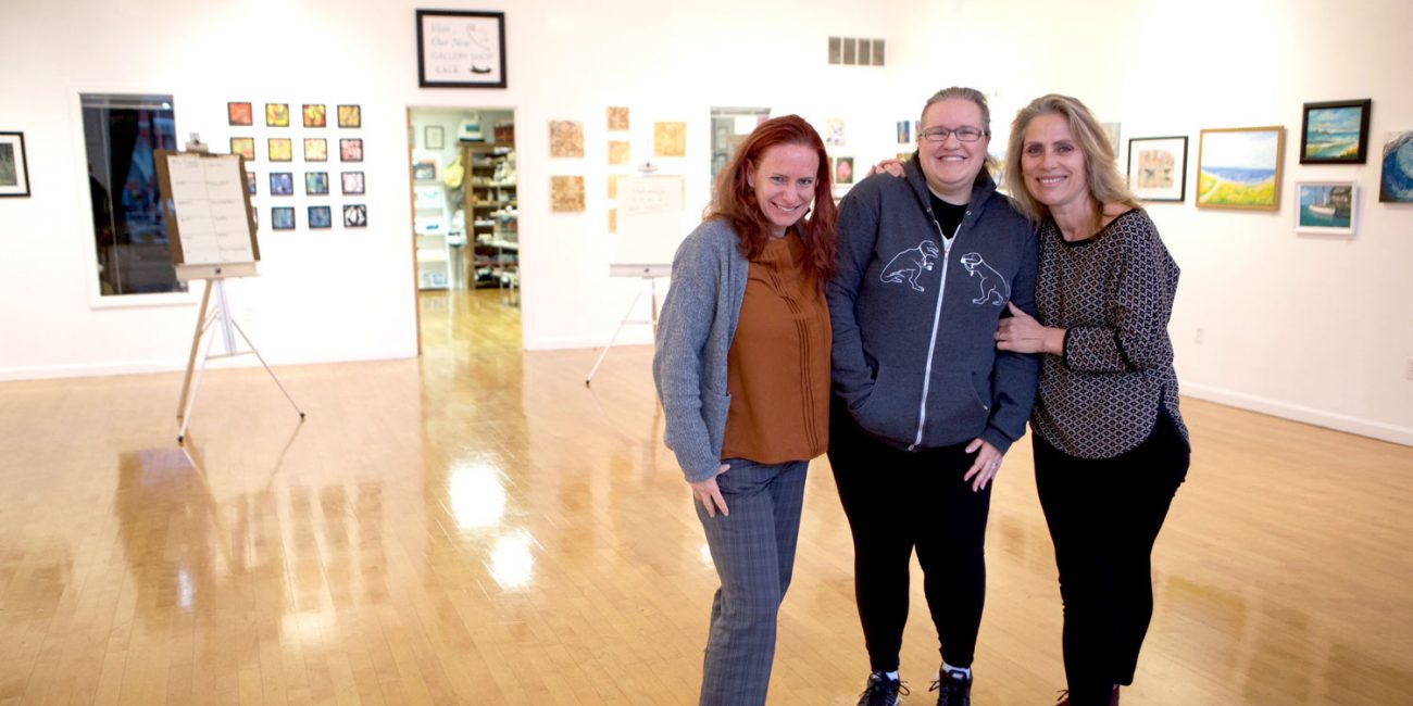two women and a man standing in an art gallery.