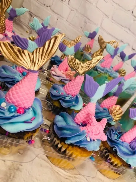 cupcakes with blue and pink frosting and gold decorations.
