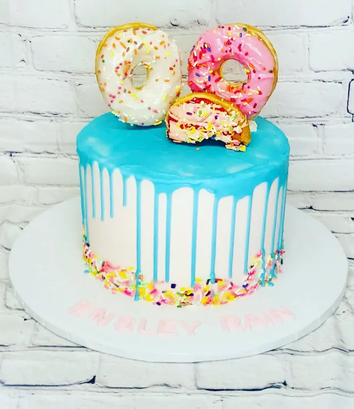 a birthday cake decorated with donuts and sprinkles.