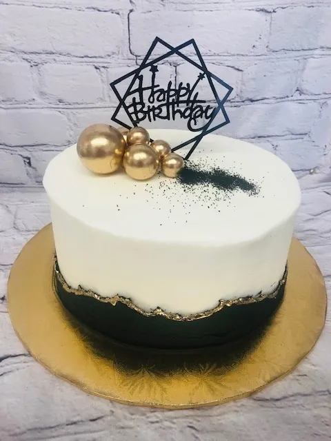a white and black cake with gold decorations.