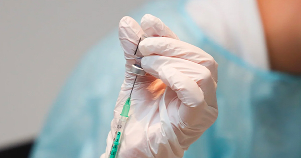 a person in white gloves holding a green needle.
