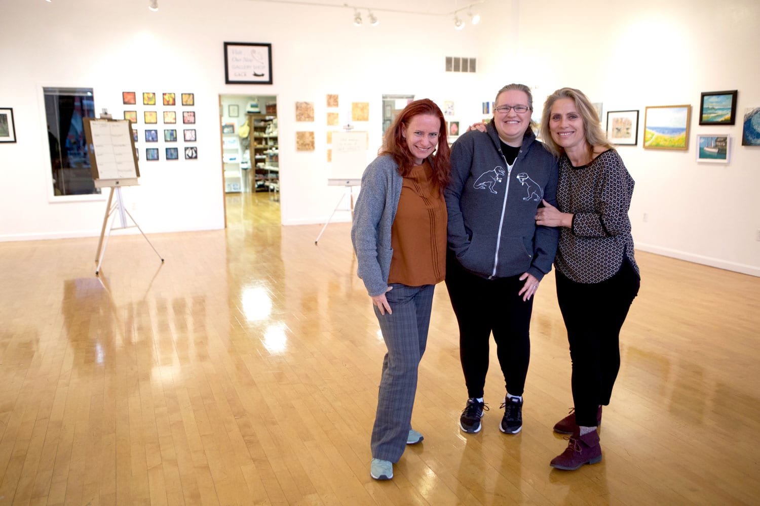 three people standing in an art gallery posing for a picture.