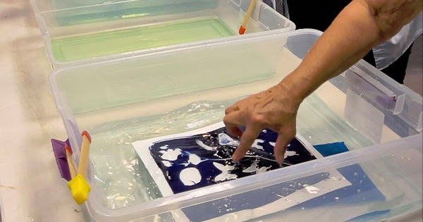 a person touching a picture in a plastic container.