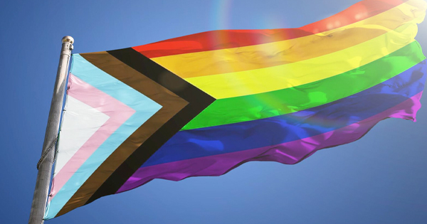 a rainbow colored kite flying in a blue sky.