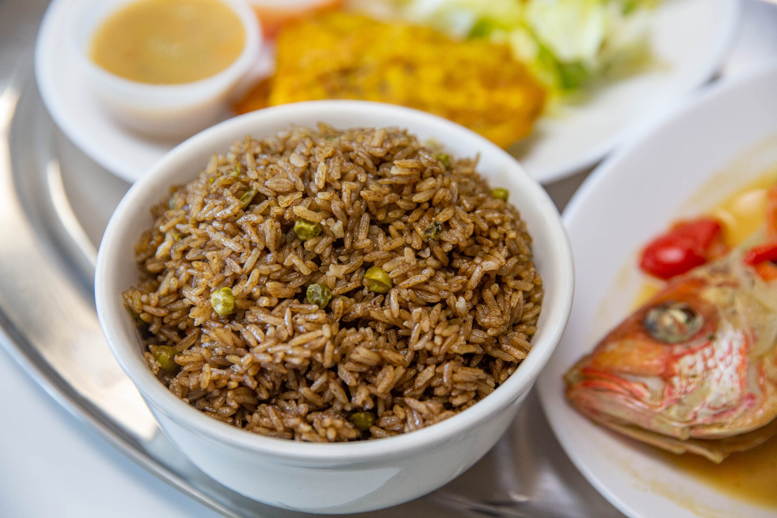 a white bowl filled with rice next to a plate of food.