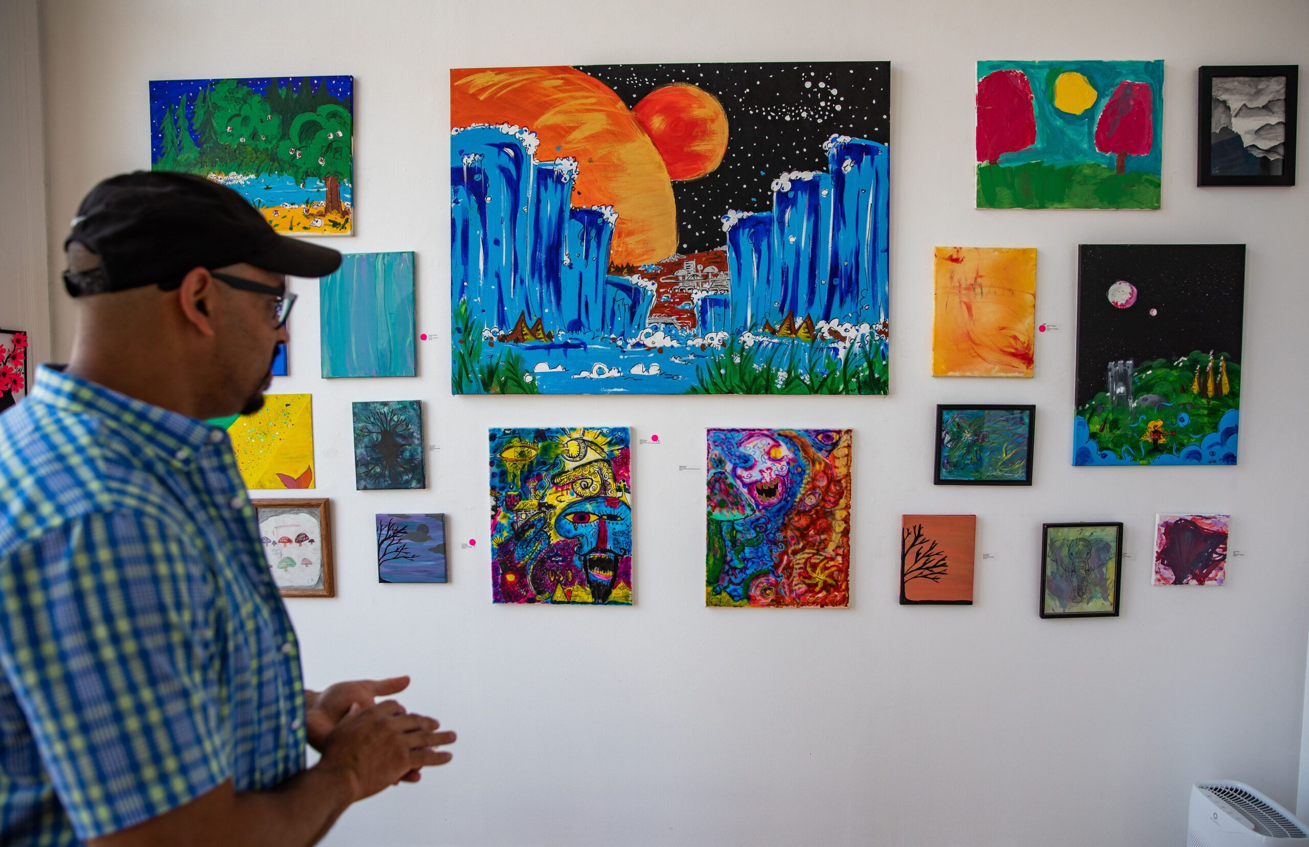 a man standing in front of a wall of art.