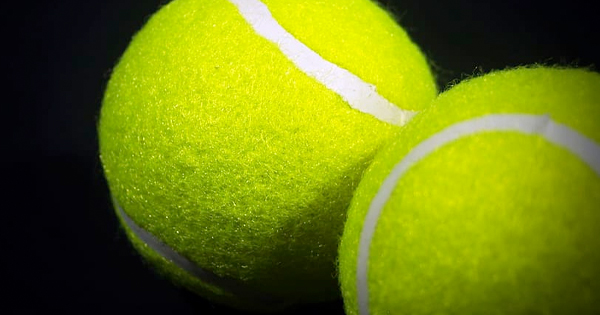 Two vivid yellow tennis balls, side by side, spark creative play and community spirit on Essex County’s courts against a bold dark backdrop.